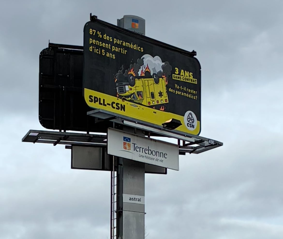 Large billboard with photo of an upturned ambulance and text with information about ongoing paramedic strike