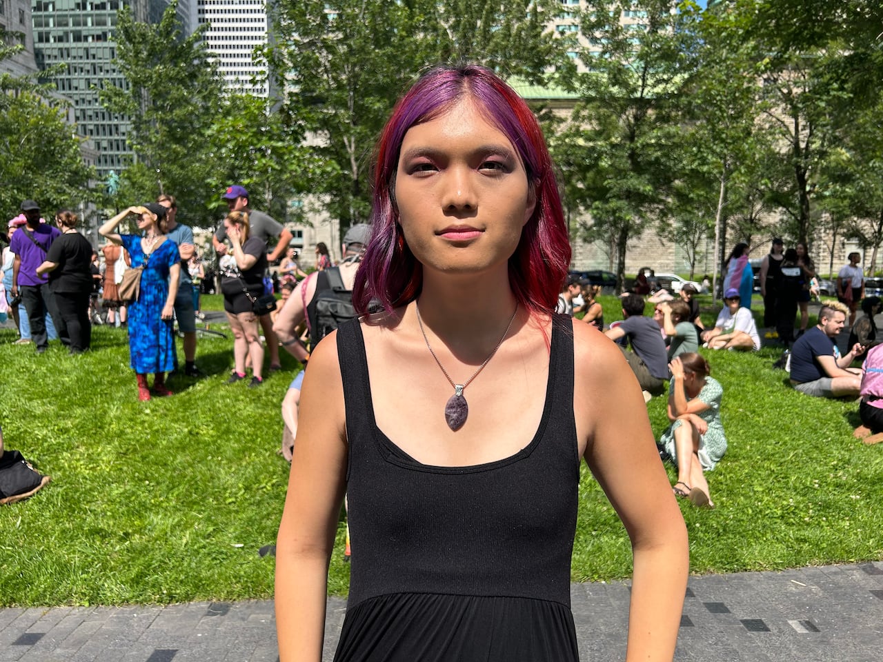 A person looks into the camera, standing among dozens of other people. 