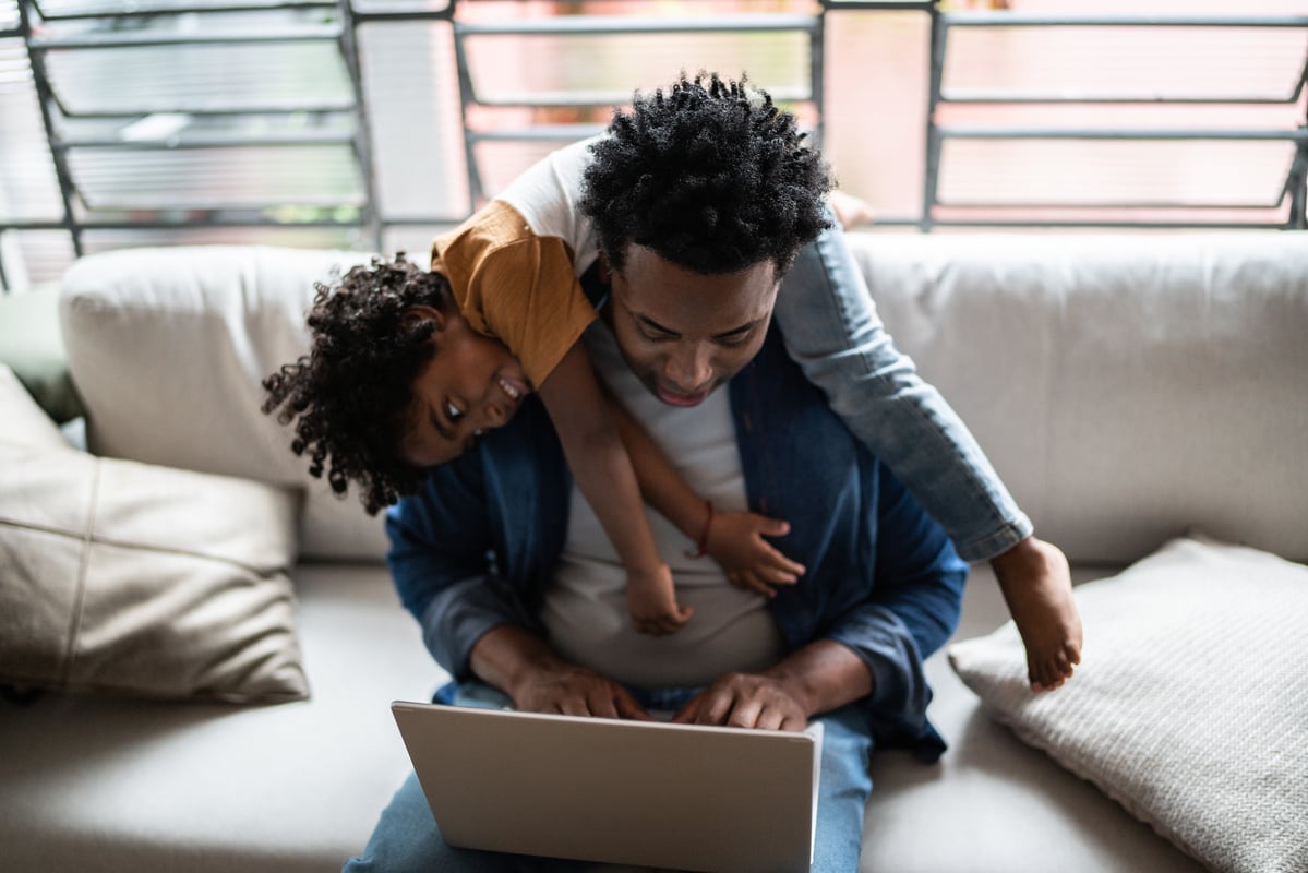 A person with a child sitting a computer.