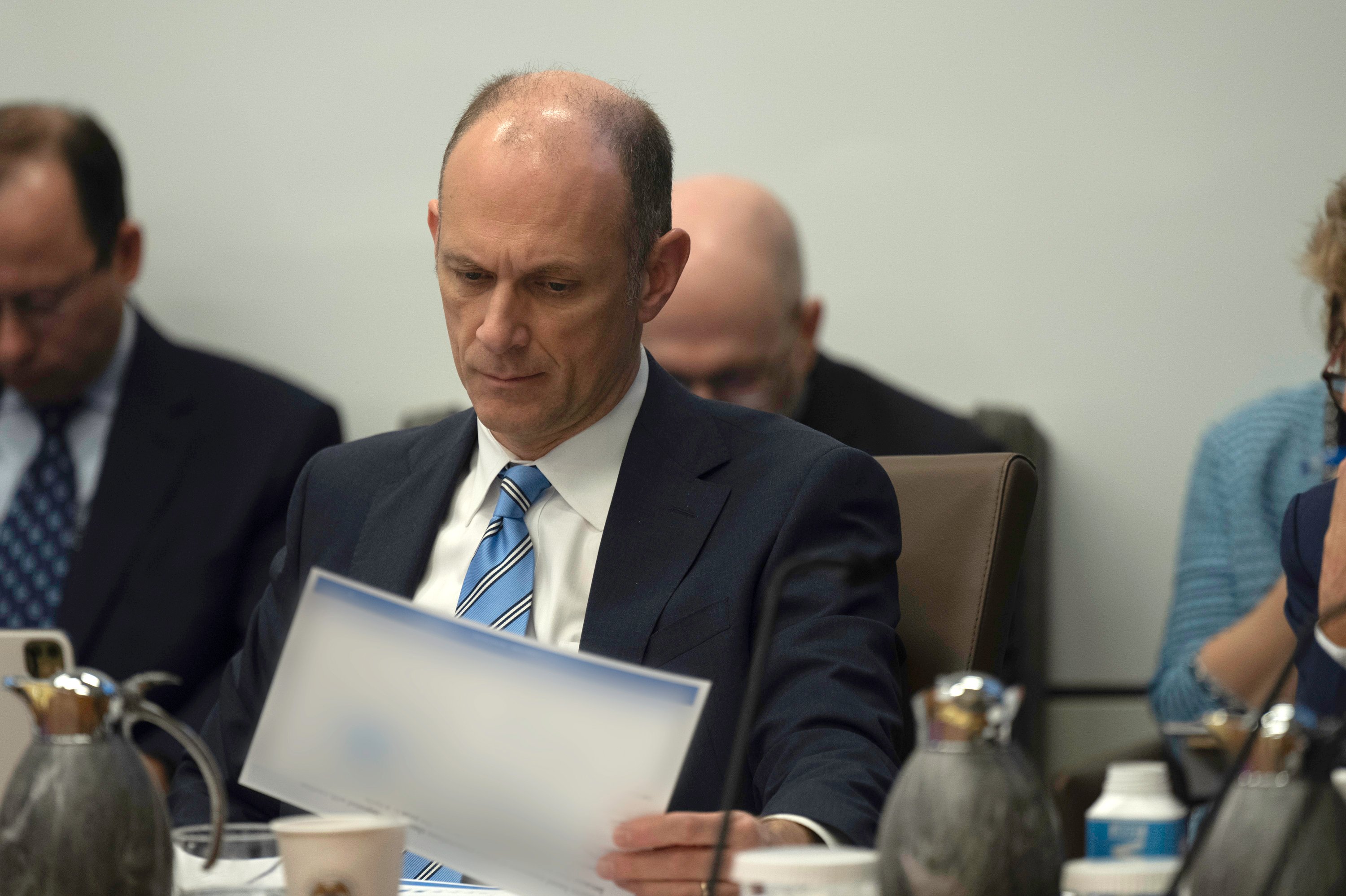 Austan Goolsbee looking over paperwork while seated at a conference room table.