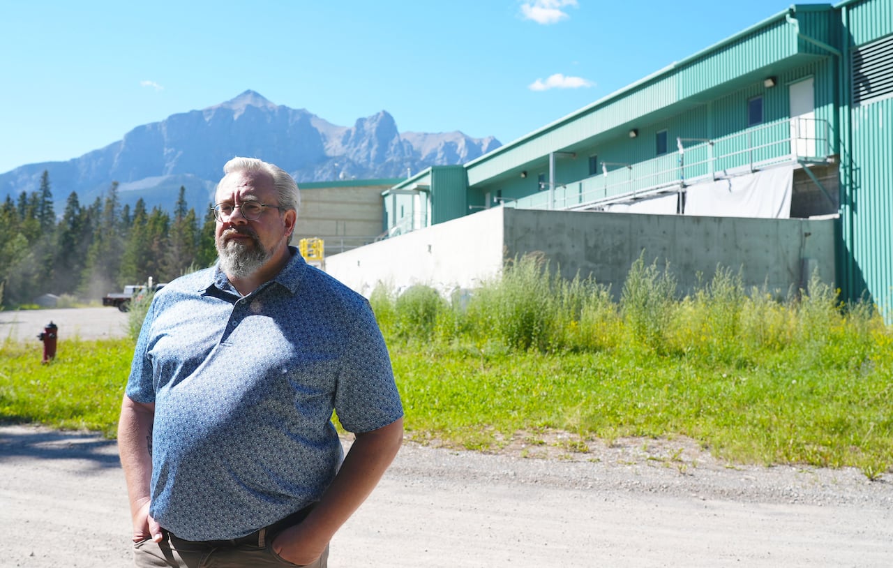 A man stands near a wastewater treatment plant.