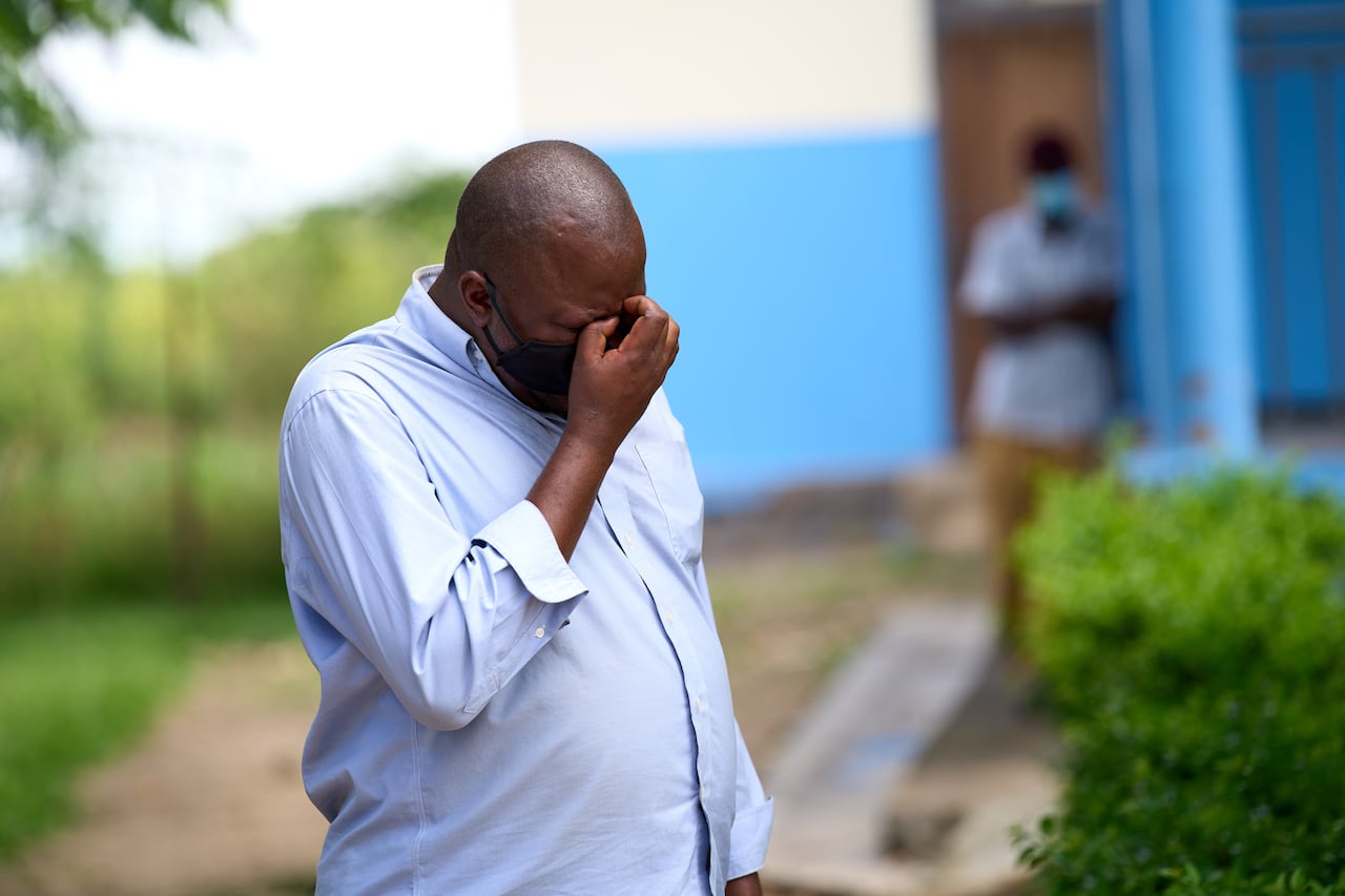 A man in mask holds his head in his hand in distress