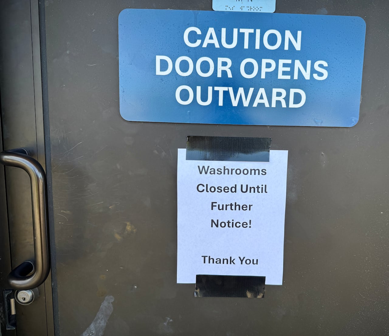 A sign says 'Caution door opens outward' and a note reading 'Washrooms closed until further notice! Thank you'.