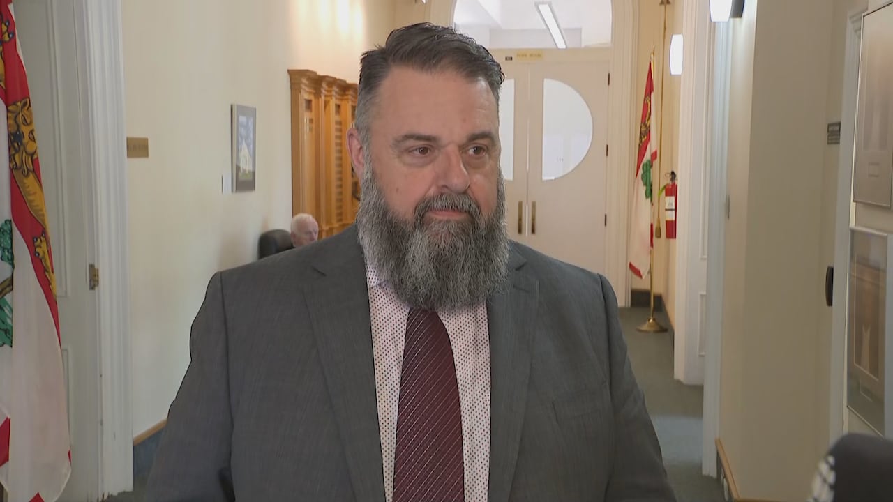A bearded man wearing a suit standing in a corridor