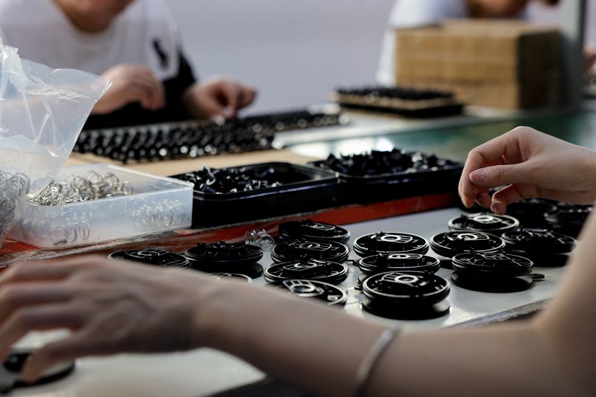 Employees work at an assembly line producing car smartphone holders in Dongguan, China.