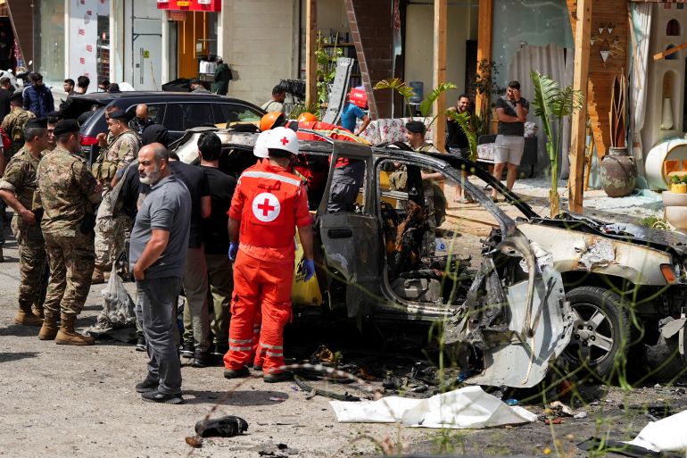 Rescuers work at the site of an Israeli strike on a car in Jiyeh