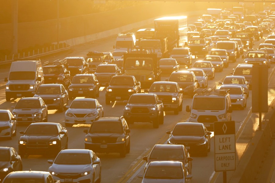 Cars sit in traffic on the highway at sunrise.