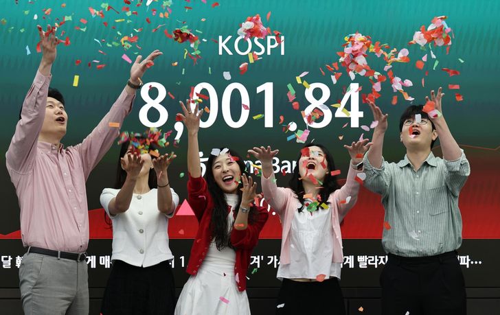 Officials celebrate KOSPI breaching the unprecedented 8,000 points mark at a dealing room in Hana Bank, Seoul, Friday. Yonhap