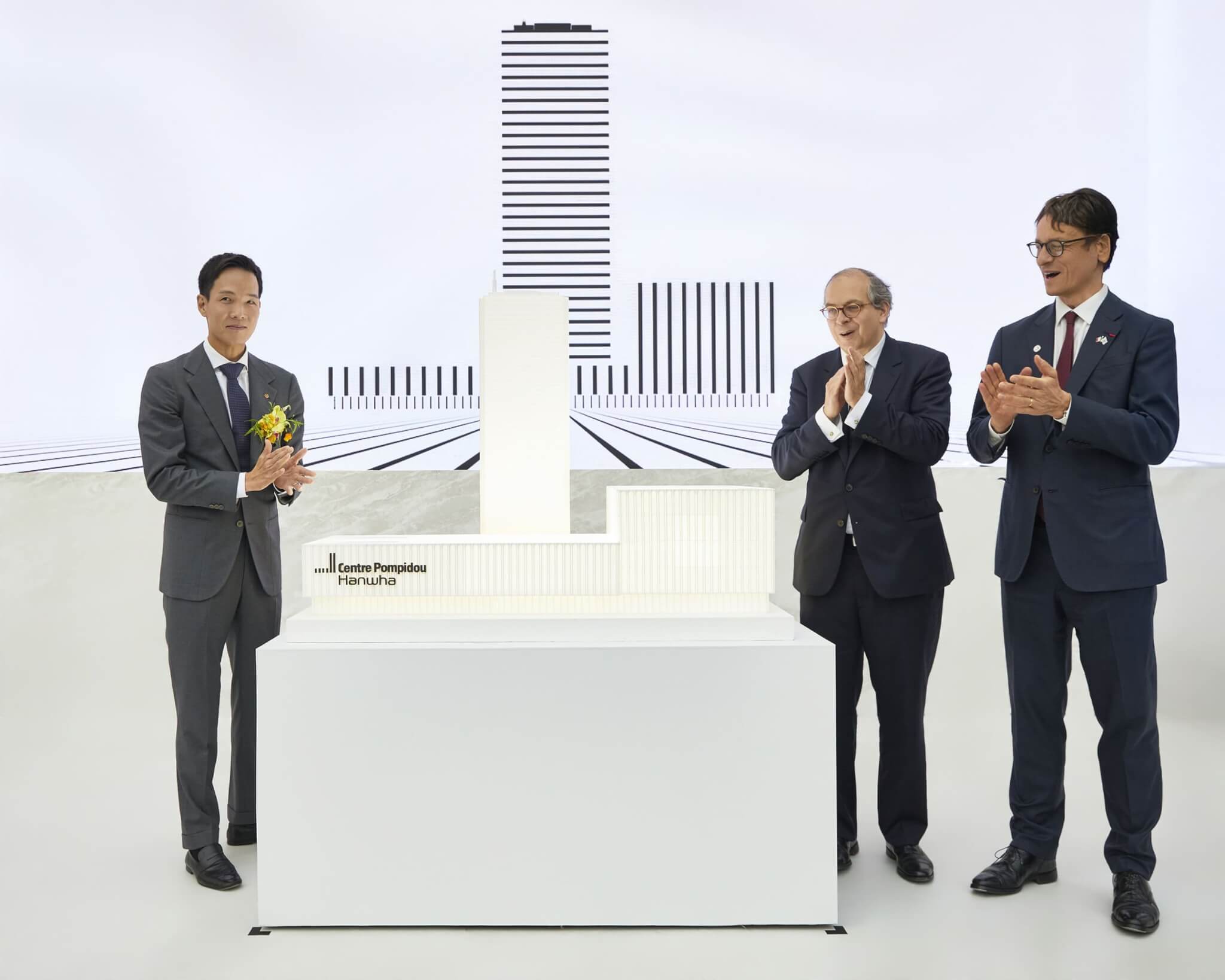 Three men beside a white architectural model of Centre Pompidou Hanwha at the museum's opening ceremony in Seoul