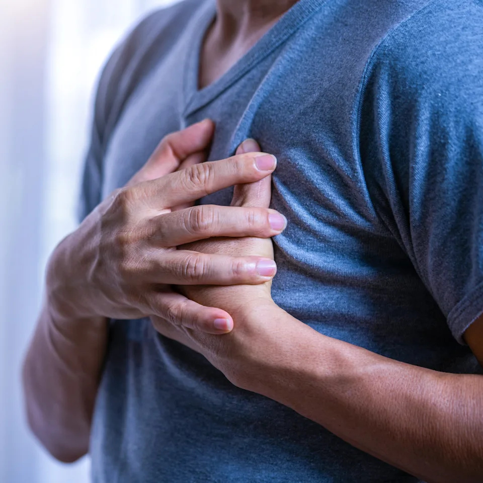 Person clutching chest, possibly experiencing discomfort or pain