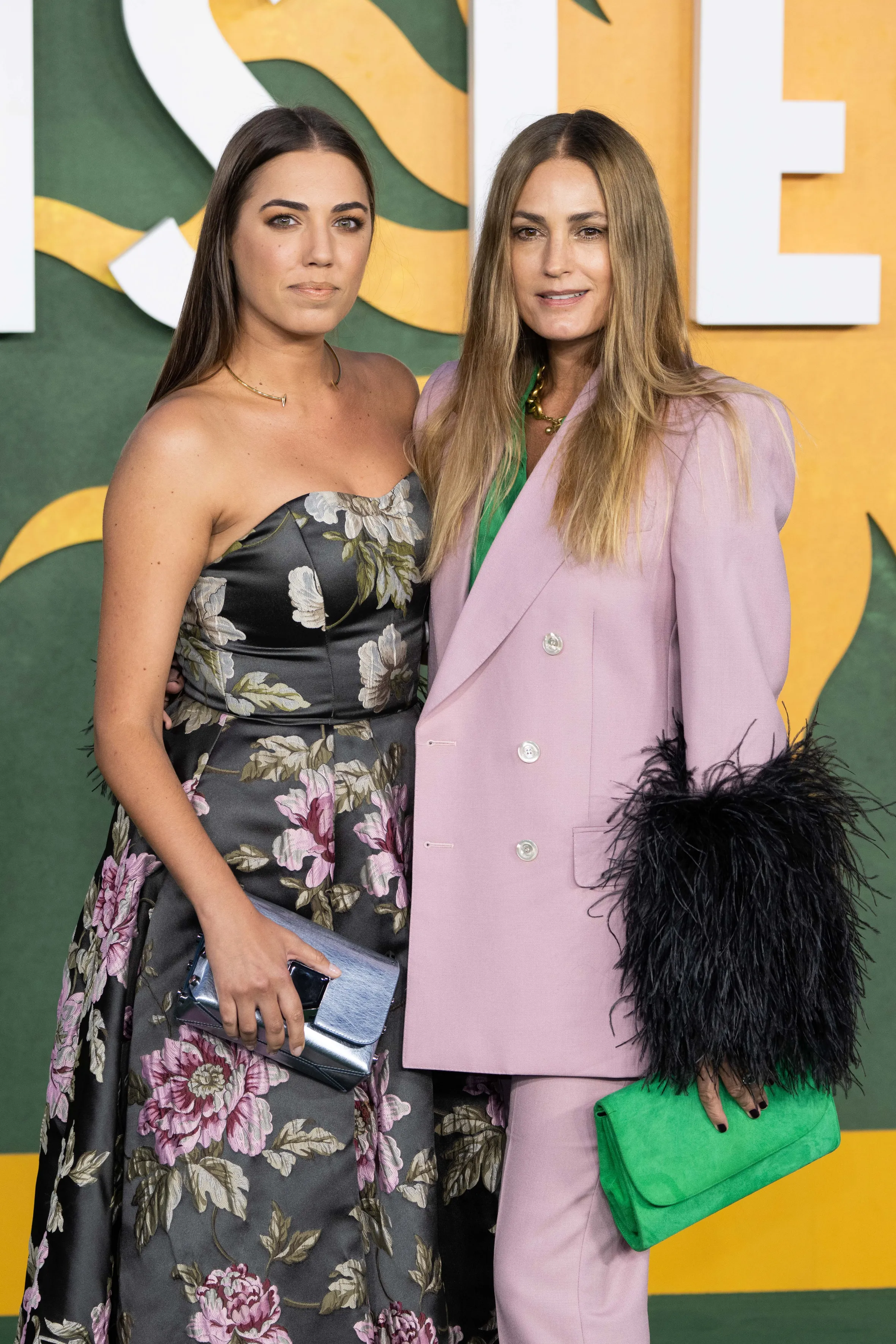 Amber Le Bon in a floral dress and Yasmin Le Bon in a pink suit with feathered sleeves.