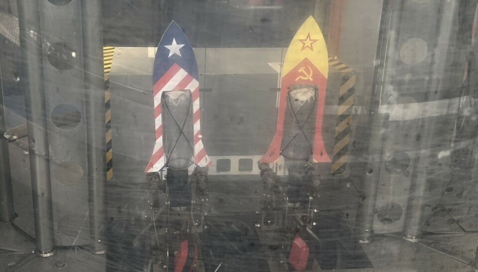 Two decorated bottle rockets on stands behind glass in an indoor science exhibit.