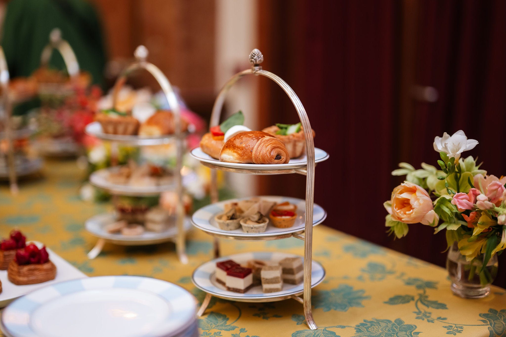 Tiered dessert stand with various pastries and floral arrangement