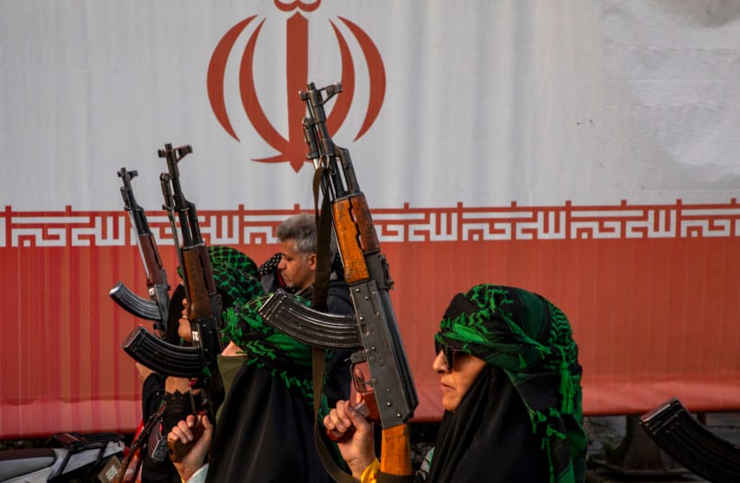 Women hold rifles in front of an Iranian flag during a pro-government National Army Day demonstration in Tehran, Iran, April 17, 2026.