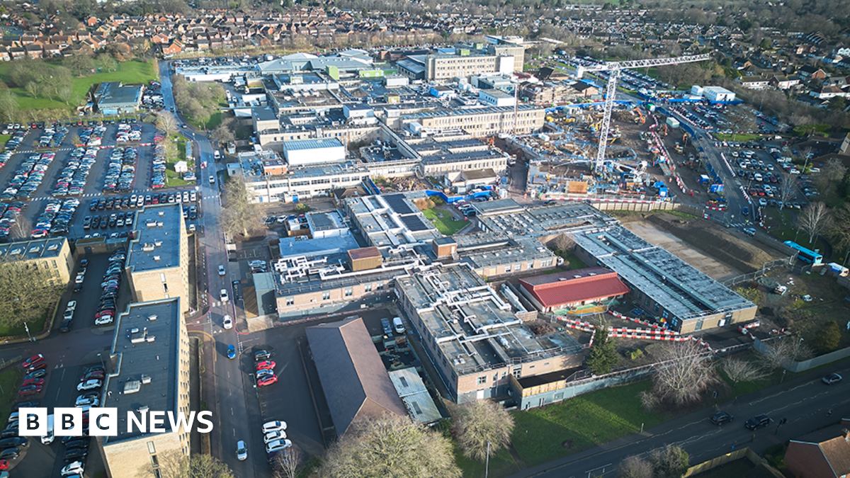 An aerial view of a hospital site with a number of large buildings surrounded by car parks and grassy areas