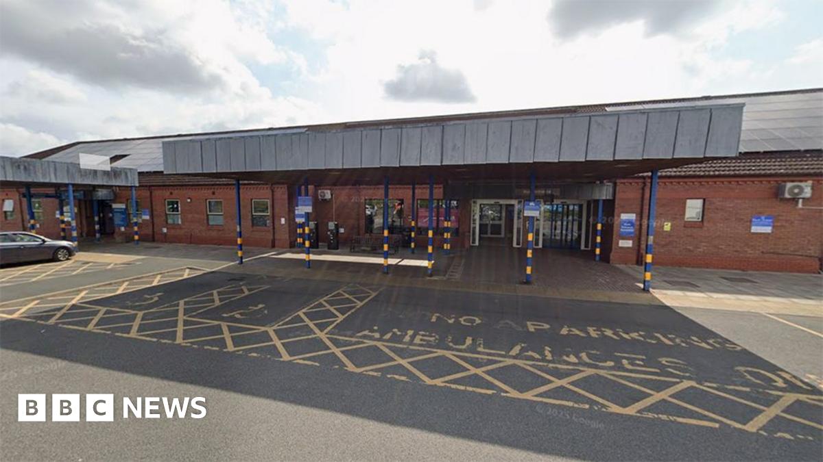 The main entrance to Bridlington Hospital. It has a grey canopy over the doors and an ambulance parking bay in front marked in yellow paint.
