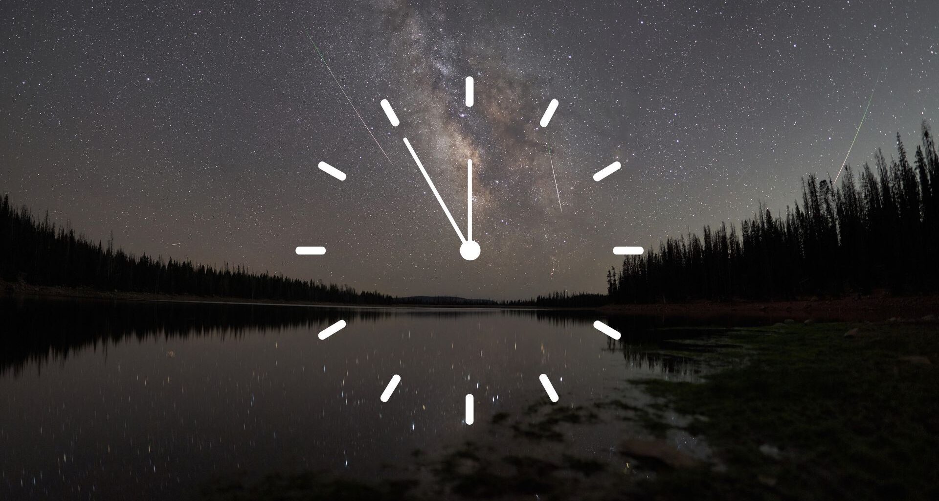 A stylized white clock face is superimposed over a night-time scene, in which meteors race through a starry sky over a lake bordered by the silhouettes of trees.
