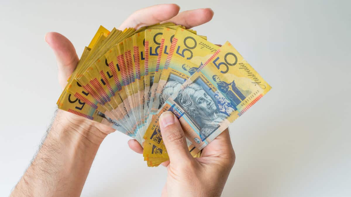 Man holding fifty Australian Dollar banknotes in his hands, symbolising dividends.