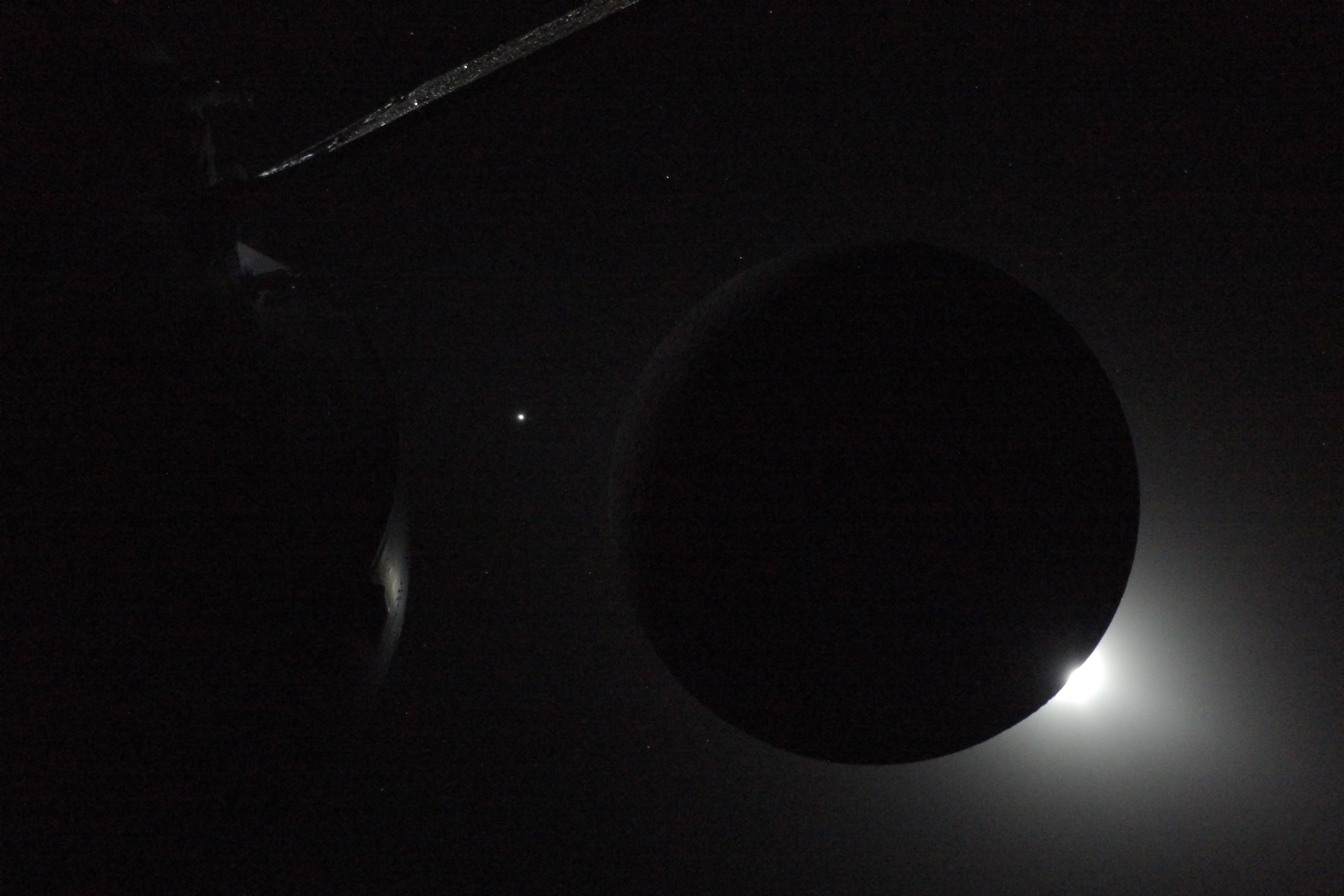 The sun busts from behind a silhouetted moon.