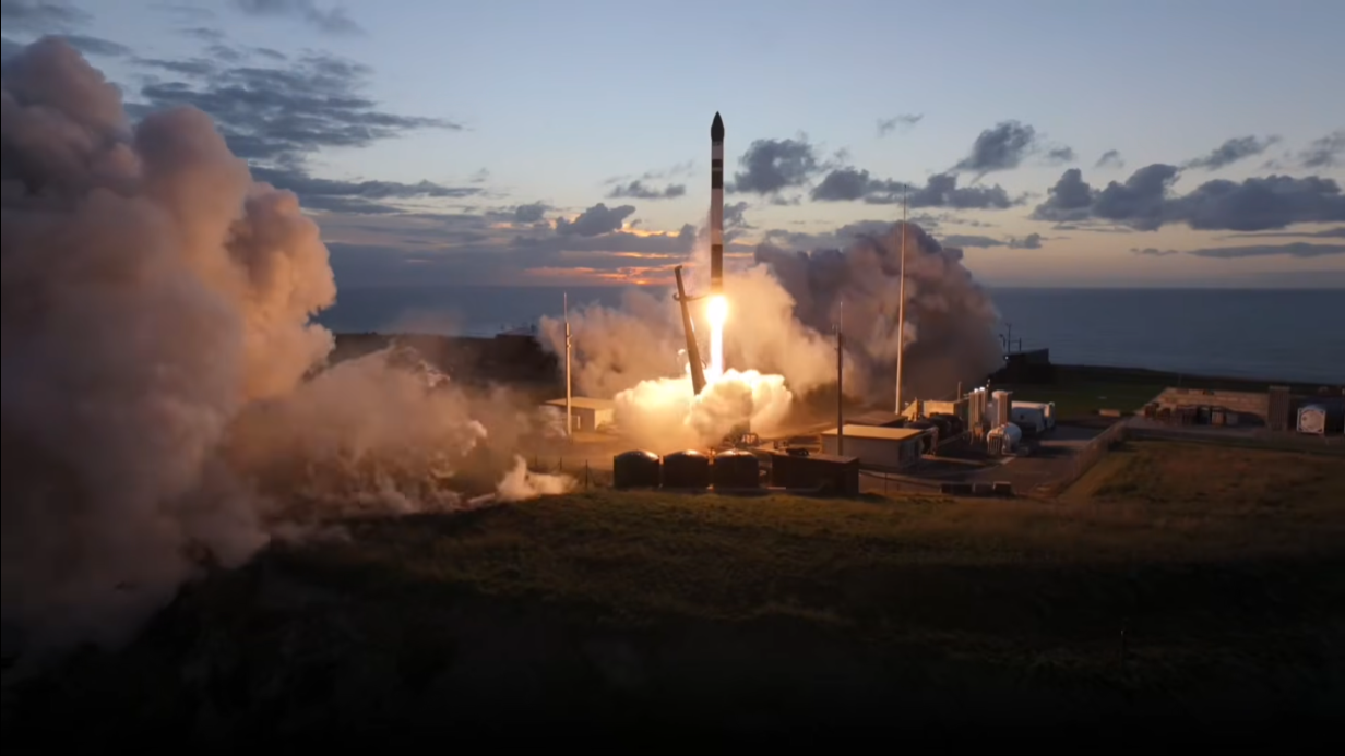 a black and white rocket launches into a dusky, cloudy sky