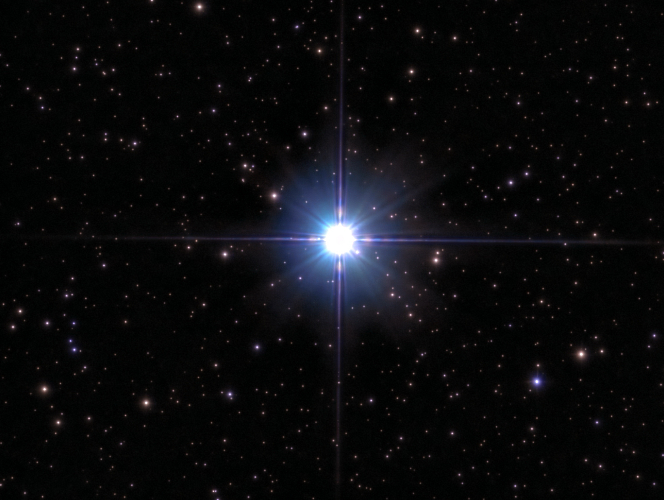 A star shines white-blue in deep space.