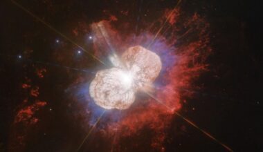 two large lobes of colorful gas radiate outward from a bright pinpoint of light