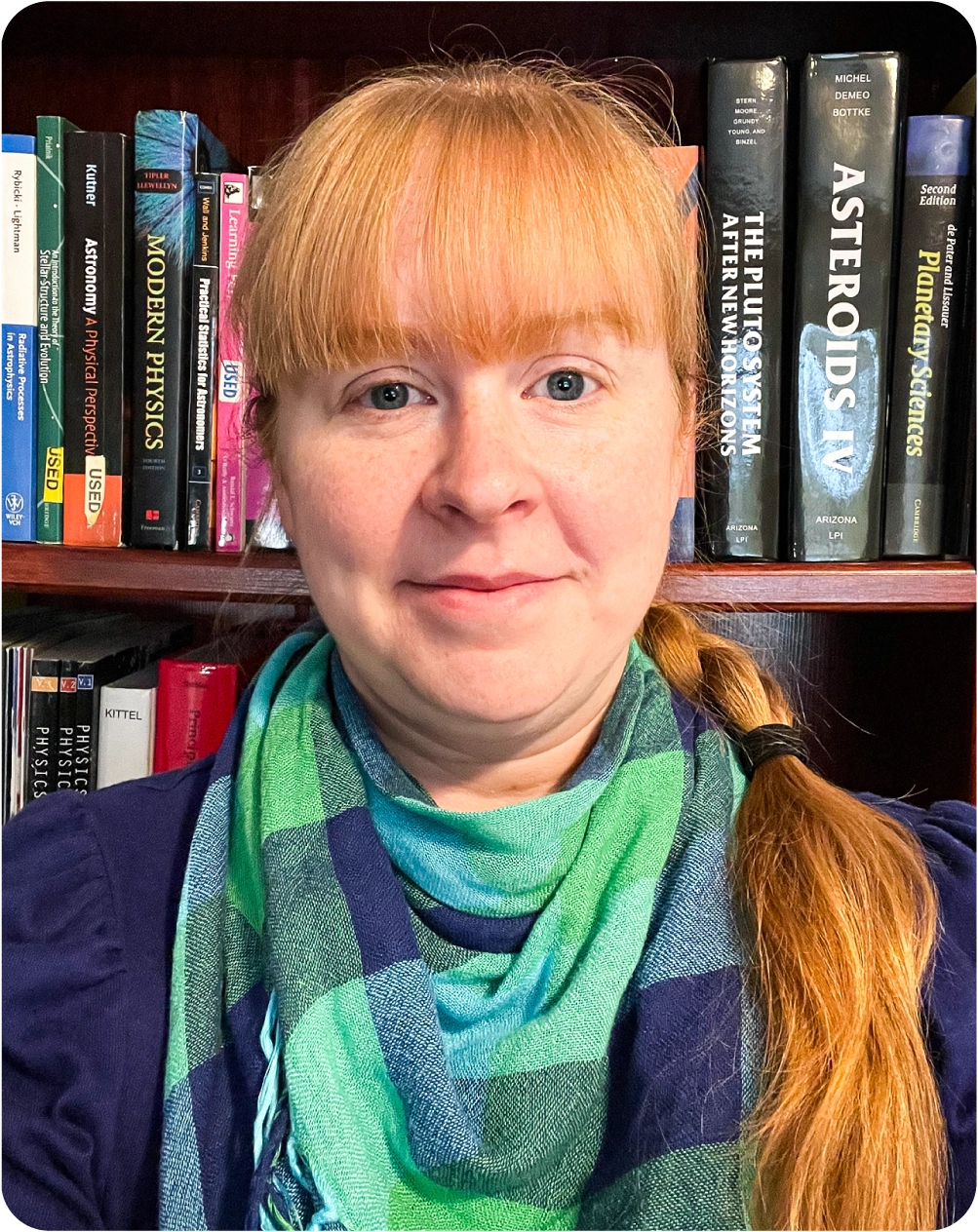 Portrait of a woman in front of a shelf full of books on physics and astronomy.