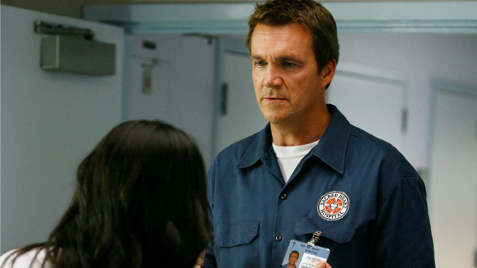 A woman looking at the Janitor's name tag in Scrubs