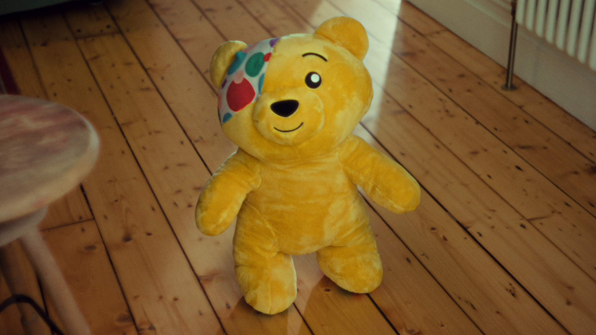 A small Pudsey bear toy on a wooden floor