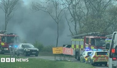 A road side image of black smoke in the air, and emergency service vehicles in Sutton.