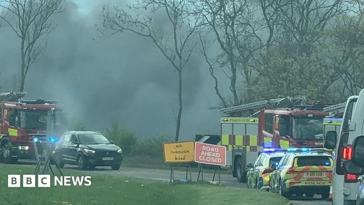 A road side image of black smoke in the air, and emergency service vehicles in Sutton.