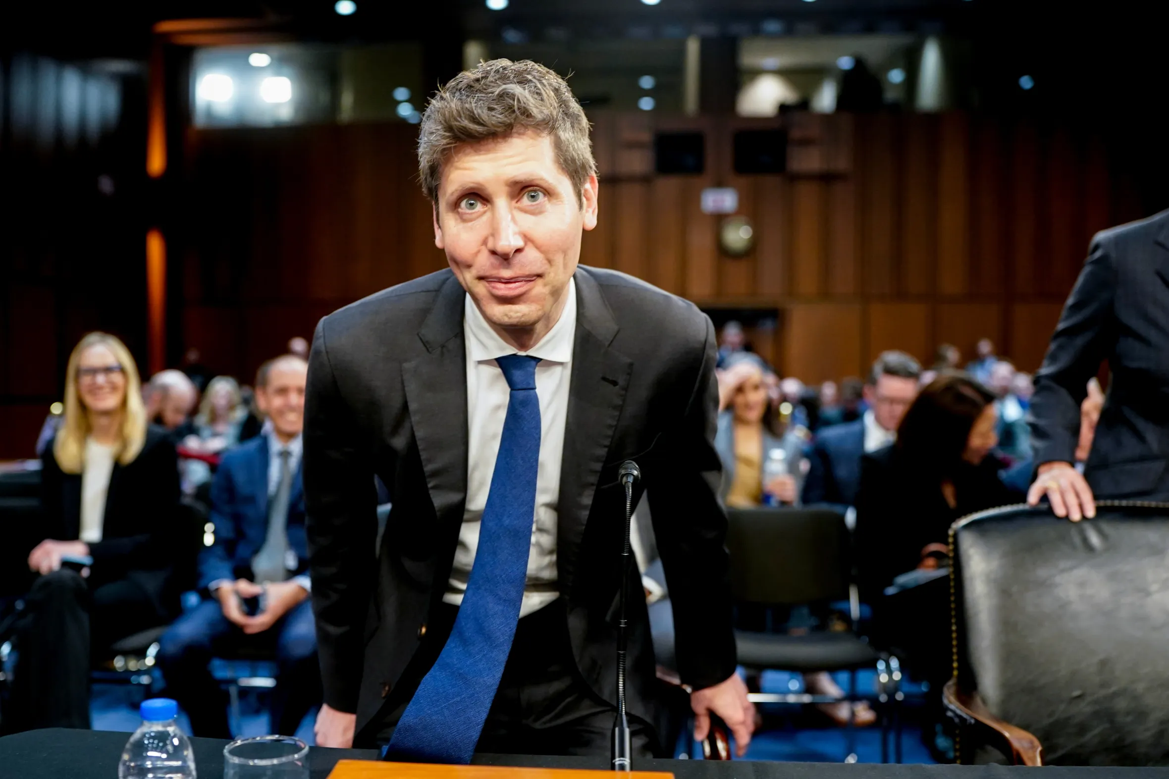 Sam Altman, CEO of OpenAI, leans over a podium at a Senate committee hearing.
