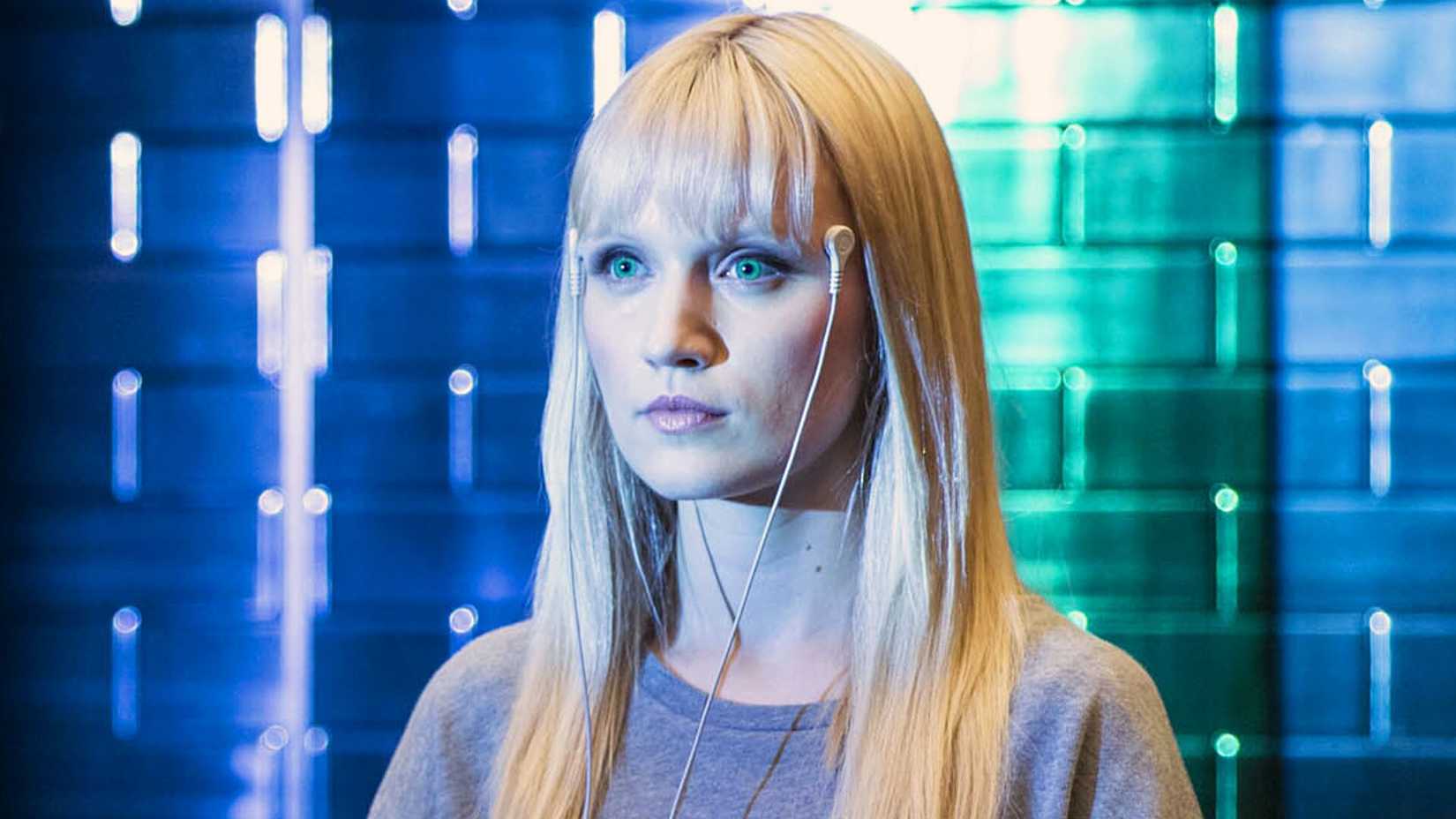 Emily Berrington as Niska in Humans in a blue and green lit room with monitors attached to her temples