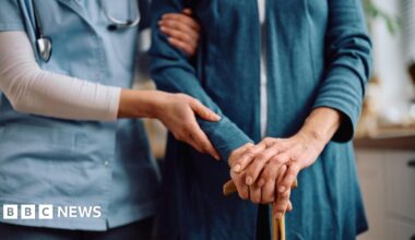 Close up of nurse and senior woman with walking cane during home visit.
