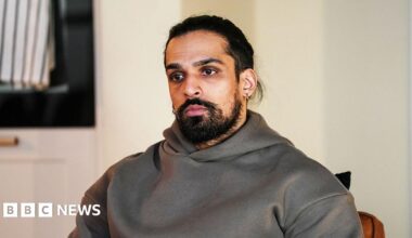 A still from EastEnders showing the character of Ravi, wearing a grey hoodie and looking into the distance.