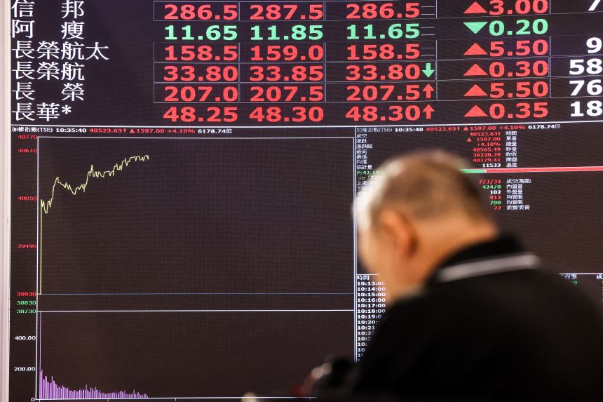 A man looks at a board displaying stock prices at the Taiwan Stock Exchange, in Taipei on May 4.