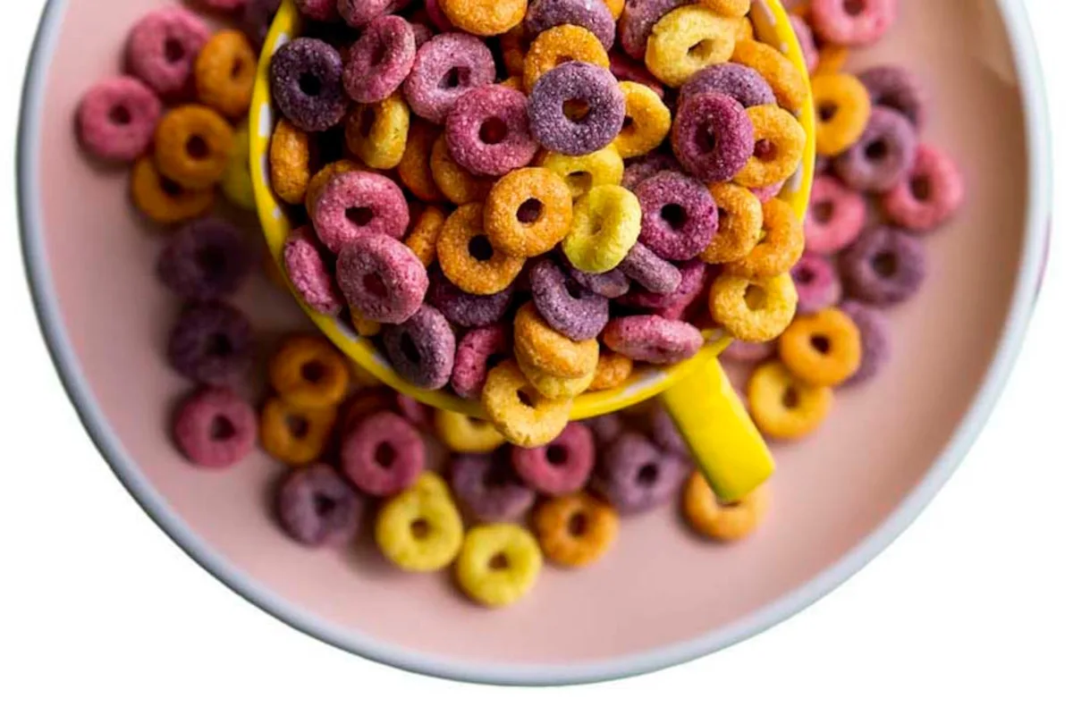Photo of an overflowing mug of multi-coloured cereal hoops