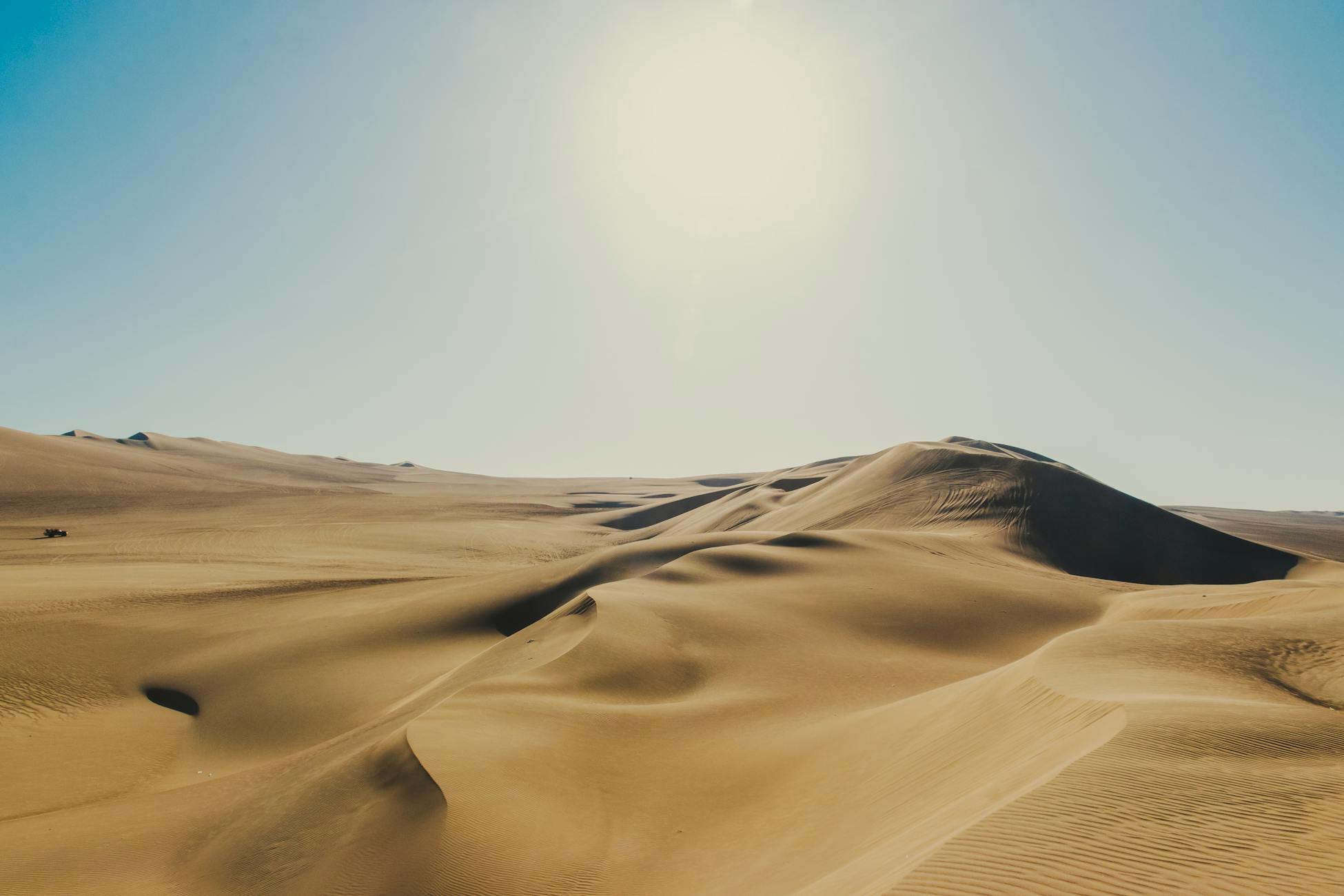 Golden sand dunes stretch under a clear sky in Ica, Peru, showcasing nature's arid beauty.