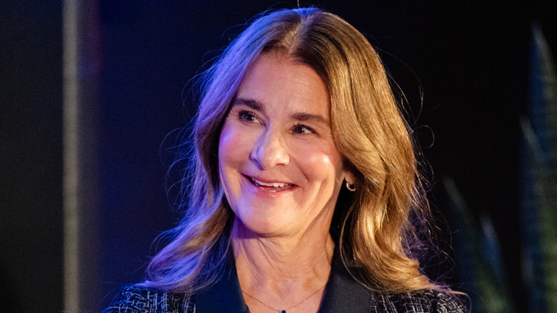 Melinda Gates laughing onstage in a collared, patterned shirt