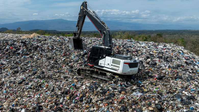 an excavator at work on a giant landfill