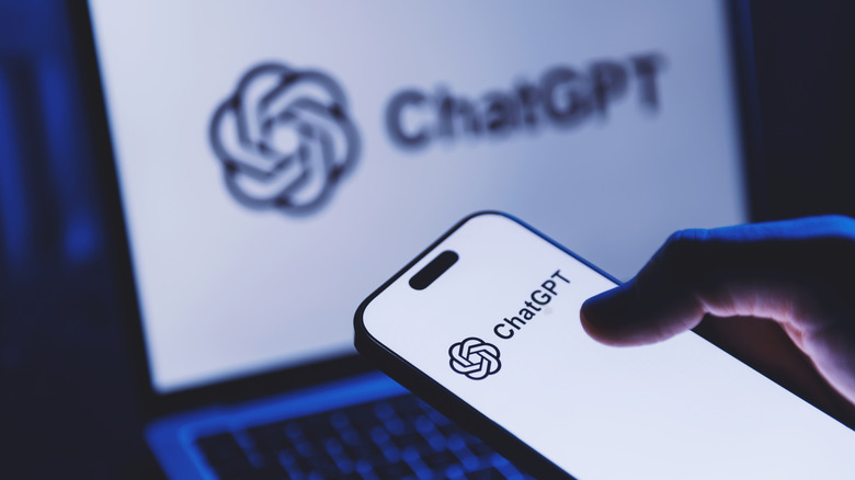 ChatGPT logo shown clearly on a smartphone in the foreground and blurred on a laptop screen in the background