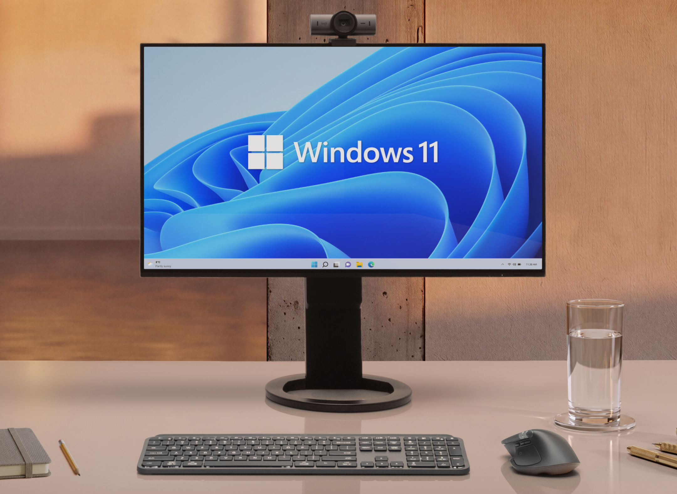 The Logitech MX Master 4 mouse on a desk next to a keyboard, glass of water, and monitor displaying Windows 11.