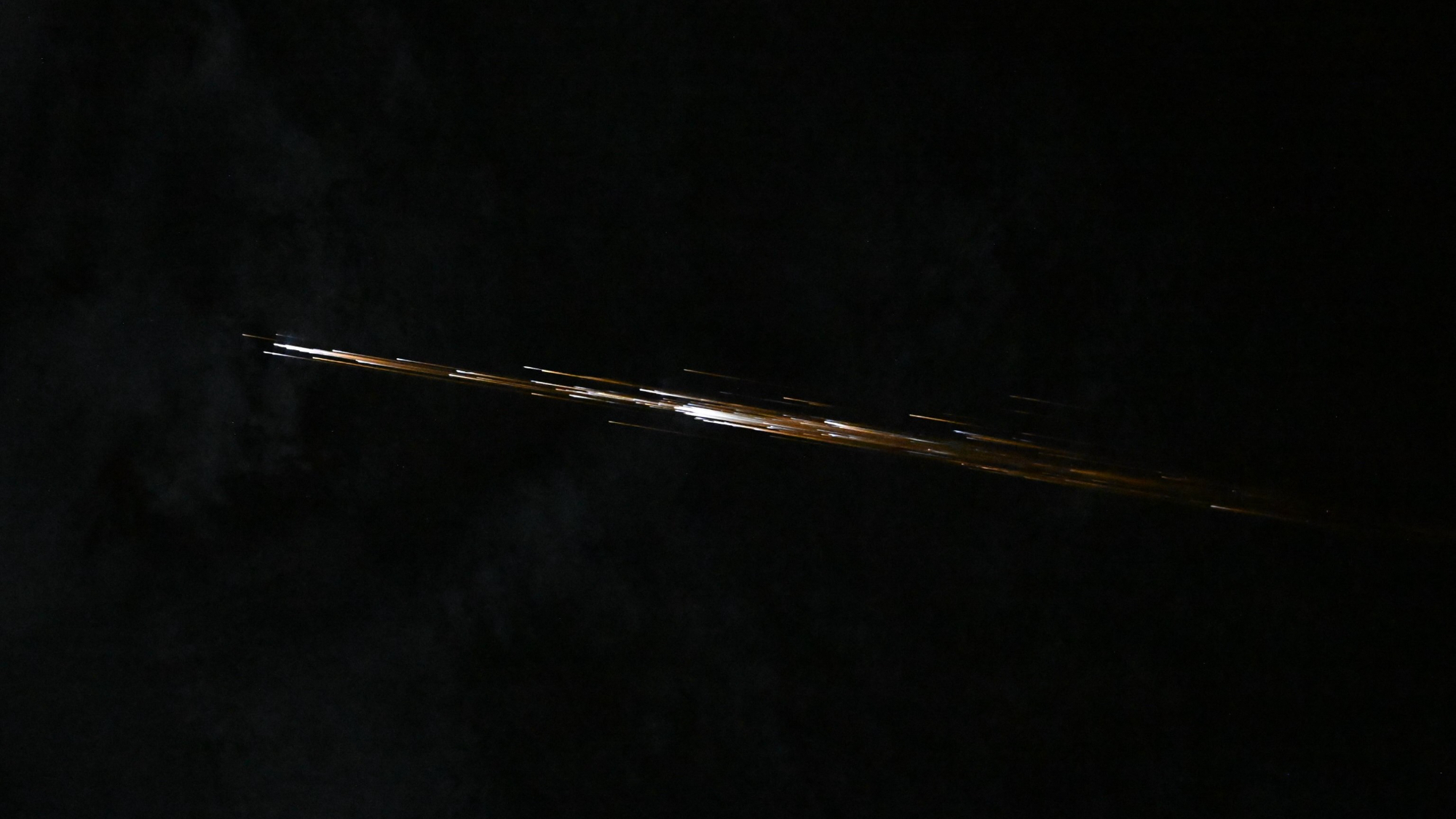 photo showing a linear streak of orange-white light against the blackness of space