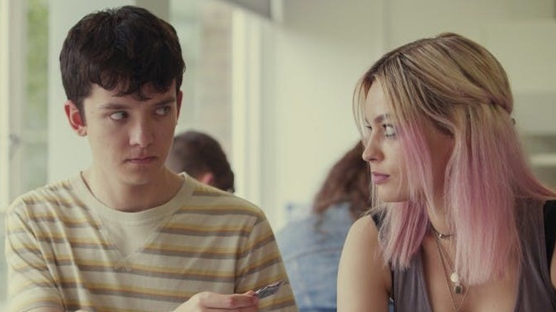 Asa Butterfield as Otis holding a wrapper to Emma Mackey as Maeve in Sex Education