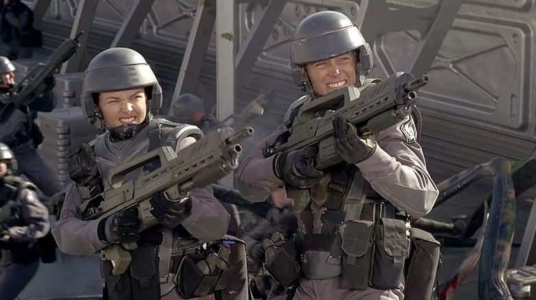 Dizzy (Dina Meyers) and Rico (Casper Van Dien) aiming their guns in Starship Troopers