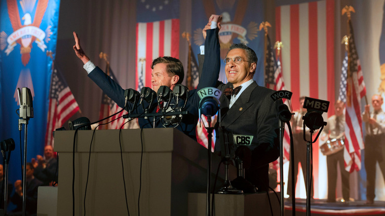 Ben Cole and John Turturro as Charles Lindbergh and Rabbi Lionel Bengelsdorf, standing at a podium in The Plot Against America.