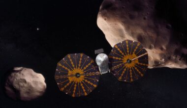 A spacecraft is depicted with a giant solar panel, circular structure on either side of its body. Two asteroids are shown in the background, the one on the right being quite a bit larger than the one on the left.