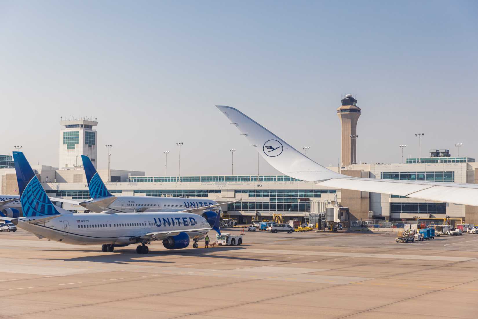United Airlines planes docked at Denver International Airport with a wing and the Lufthansa Logo in the foreground.