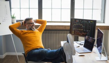 An investor relaxes in front of a computer screen.