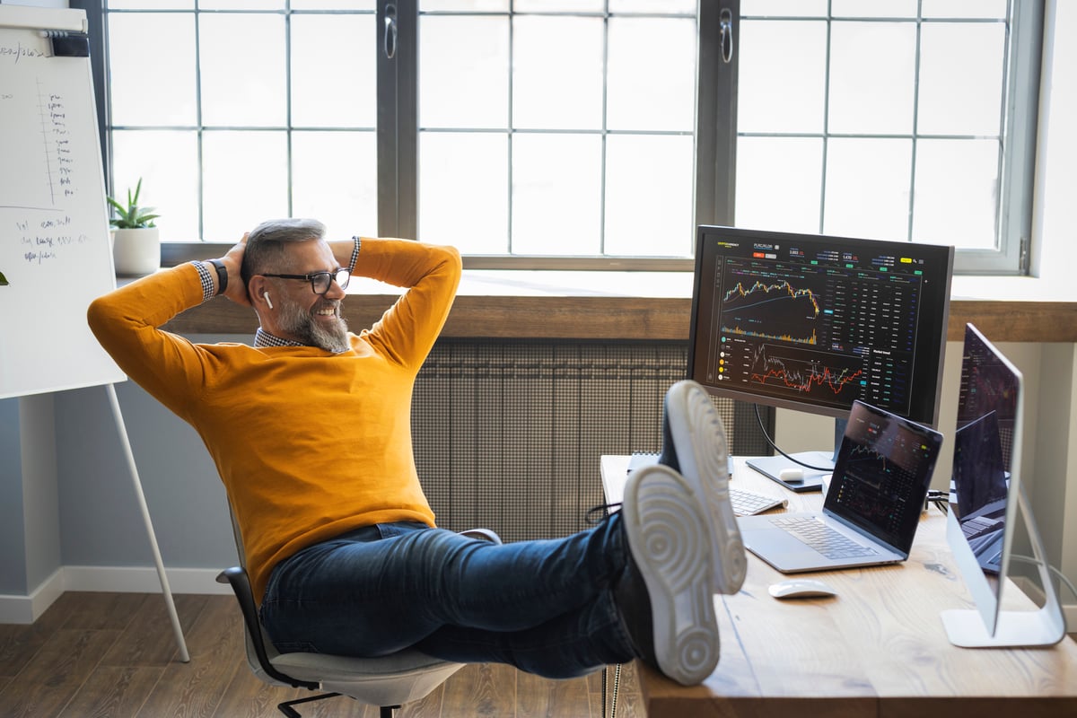 An investor relaxes in front of a computer screen.